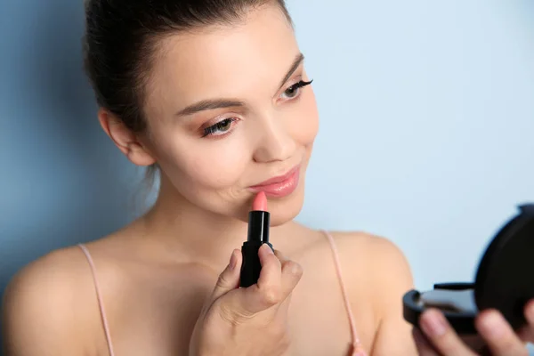 Ung kvinna applicera läppstift på färgbakgrund. Professionell makeup produkter — Stockfoto