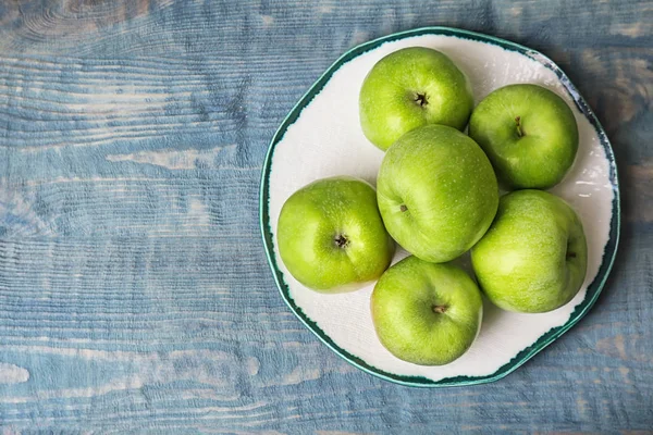 Тарелка со свежими зелеными яблоками на деревянном фоне, вид сверху — стоковое фото