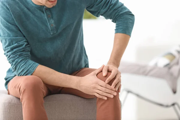 Young man suffering from knee pain at home — Stock Photo, Image