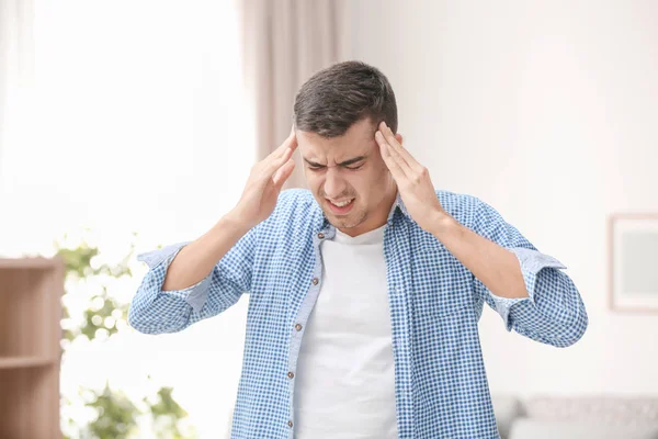 Giovane uomo che soffre di mal di testa a casa — Foto Stock