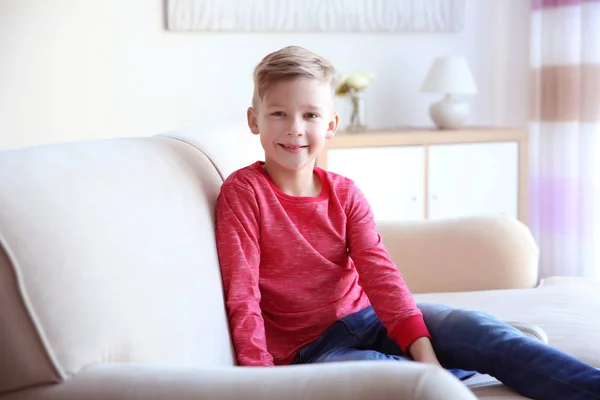 Schattig jongetje zittend op de bank, binnen — Stockfoto