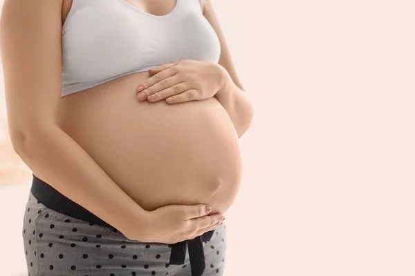 Femme enceinte après application de crème corporelle sur fond flou, gros plan — Photo