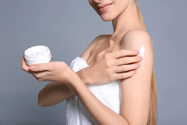 Young woman with jar of body cream on color background — Stock Photo, Image