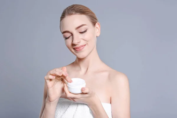 Young woman with jar of body cream on color background — Stock Photo, Image