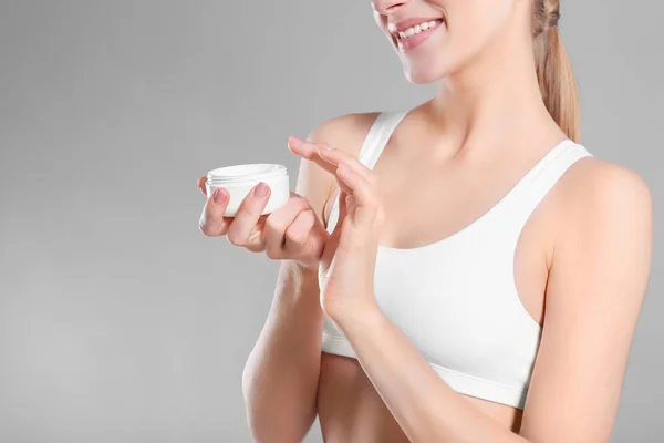 Mujer joven con tarro de crema corporal sobre fondo de color —  Fotos de Stock