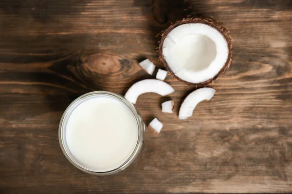 Vaso de leche de coco y nuez fresca sobre fondo de madera, vista superior — Foto de Stock