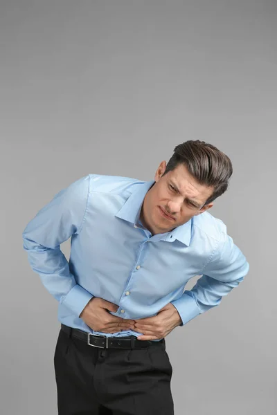 Young man suffering from abdominal pain on grey background — Stock Photo, Image