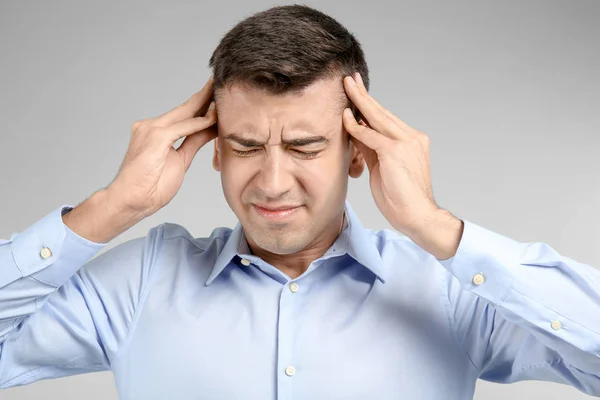Fiatal férfi szenved fejfájás-ra könnyű háttér — Stock Fotó