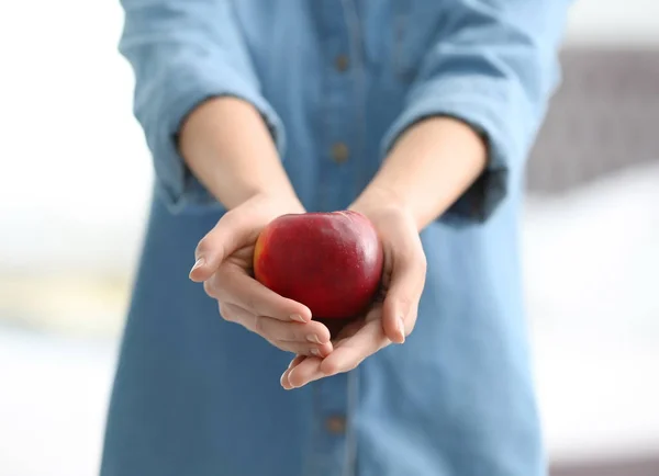 Mujer sosteniendo manzana roja madura sobre fondo borroso, primer plano — Foto de Stock