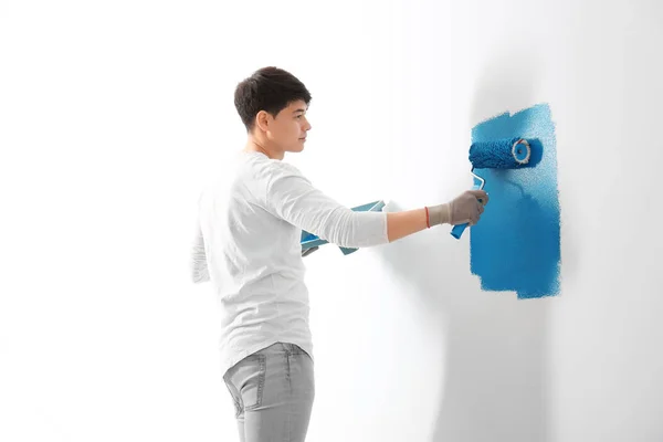 Male decorator painting wall with roller indoors — Stock Photo, Image