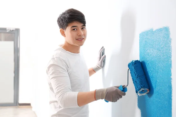 Männlicher Dekorateur bemalt Wand mit Roller drinnen — Stockfoto