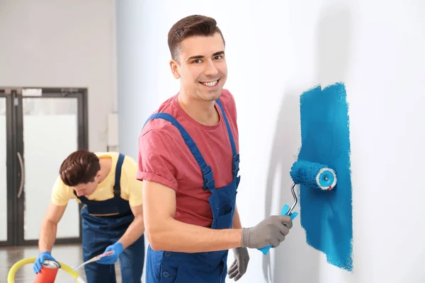 Чоловічий декоратор малює стіну з валиком в приміщенні — стокове фото