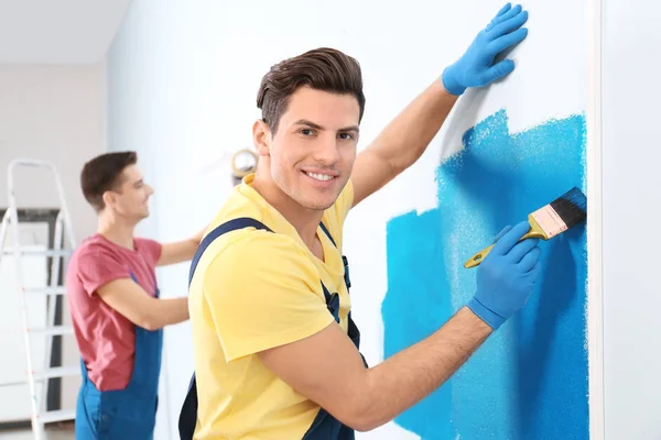 Manliga dekoratör målning vägg med borste inomhus — Stockfoto