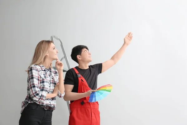 Male decorator and young woman choosing color for walls in empty room — Stock Photo, Image