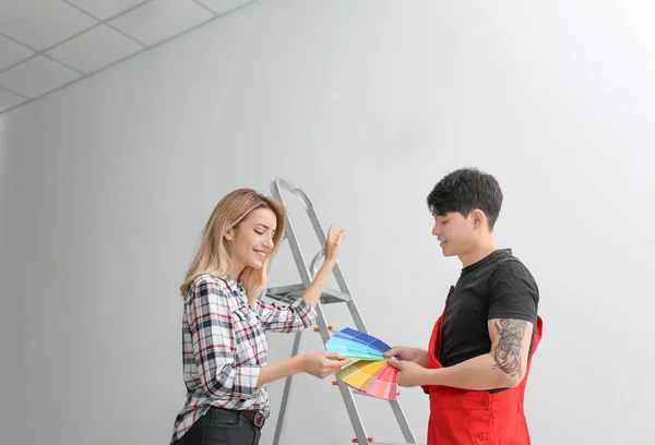 Male decorator and young woman choosing color for walls in empty room — Stock Photo, Image