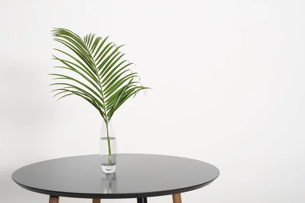 Hoja tropical en jarrón de vidrio sobre mesa interior. Idea para un interior moderno y elegante — Foto de Stock