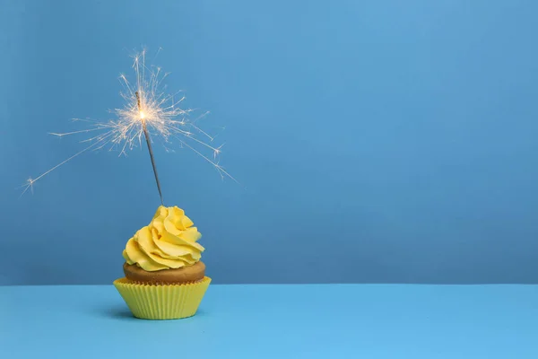 Birthday cupcake with sparkler on color background — Stock Photo, Image