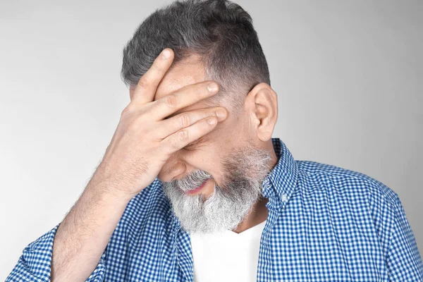 Man suffering from headache on light background — Stock Photo, Image