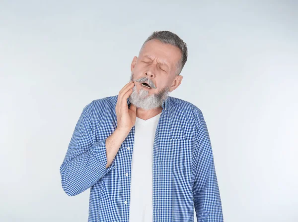 Man suffering from toothache on light background — Stock Photo, Image