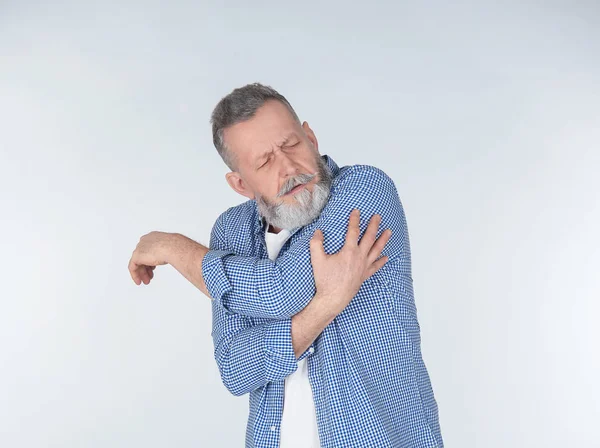 Man suffering from arm pain on light background — Stock Photo, Image