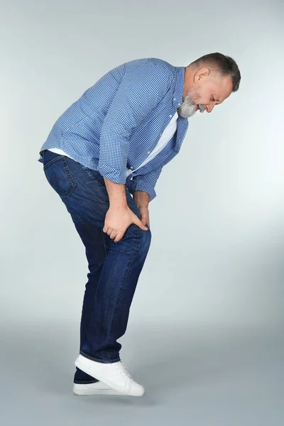 Muž trpí bolestí kolena na světlé pozadí — Stock fotografie