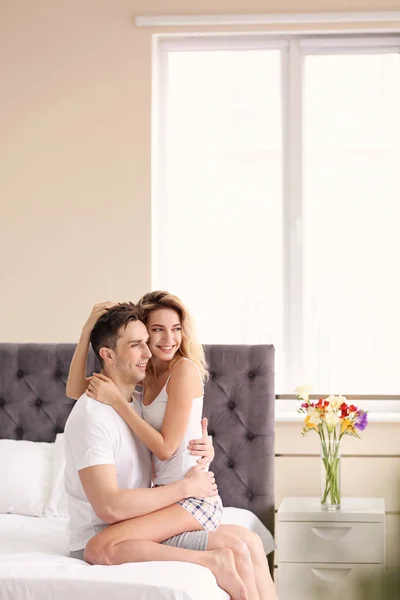 Feliz joven pareja abrazándose en la cama en casa — Foto de Stock