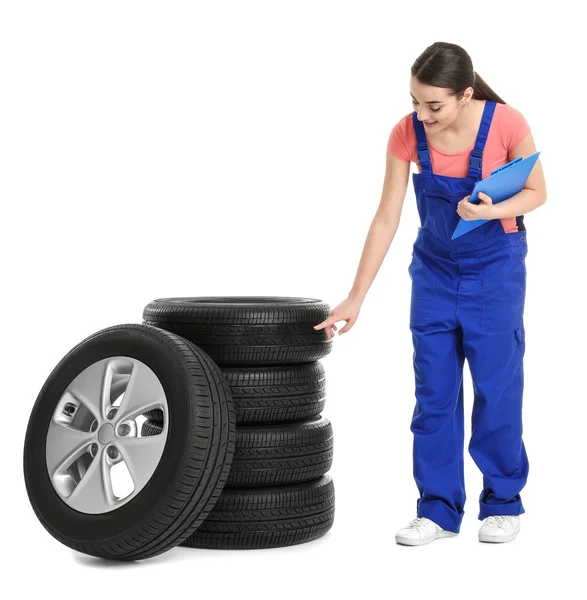 Feminino mecânico em uniforme com pneus de carro e área de transferência no fundo branco — Fotografia de Stock