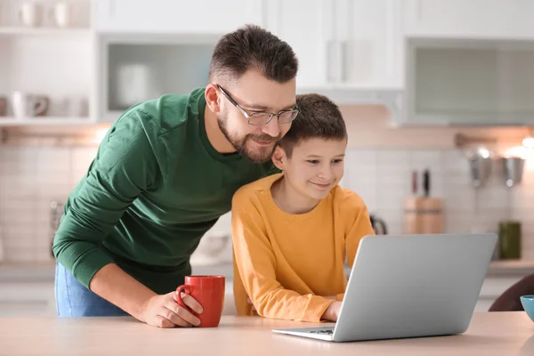 Kleine jongen en zijn papa met laptop in de keuken — Stockfoto