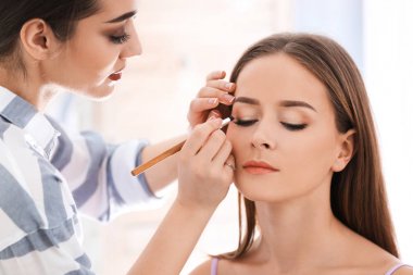 Profesyonel visage sanatçı salonda kadının yüzünde makyaj uygulamak