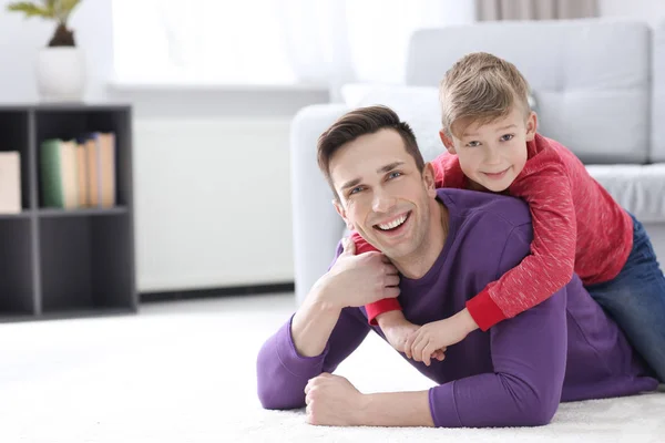 Son som kramar sin pappa på golvet hemma — Stockfoto
