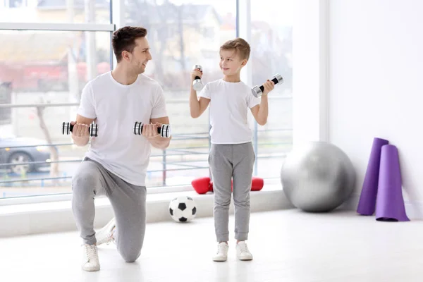 Otec a jeho syn trénink s činkami v posilovně — Stock fotografie