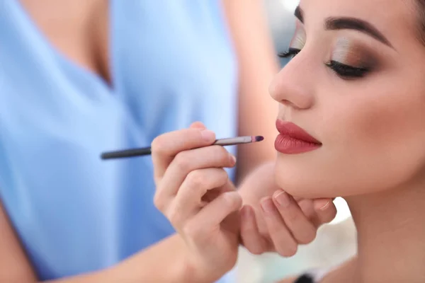 Artista de visagem profissional aplicando maquiagem no rosto da mulher no salão, close-up — Fotografia de Stock