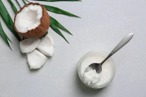 Tarro con aceite de coco y trozos de nuez sobre fondo gris — Foto de Stock