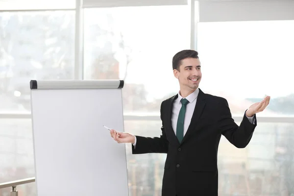 Pelatih bisnis memberikan presentasi pada papan bagan flip di dalam ruangan — Stok Foto