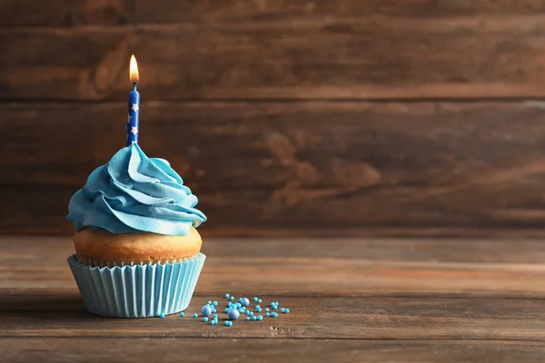 Delicioso cupcake de cumpleaños con vela encendida en la mesa de madera —  Fotos de Stock