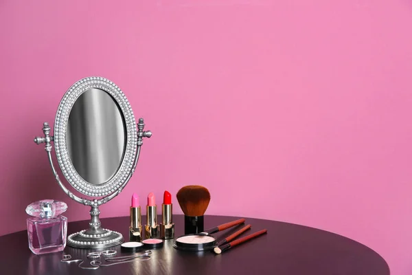 Elegante specchio, prodotti per il trucco e accessori sul tavolo vicino alla parete di colore — Foto Stock