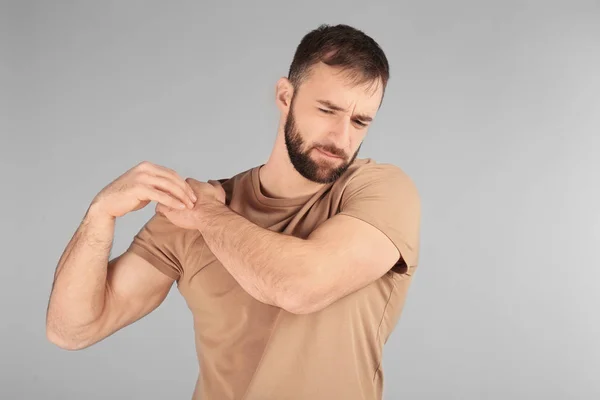 Young man suffering from pain in shoulder on light background — Stock Photo, Image