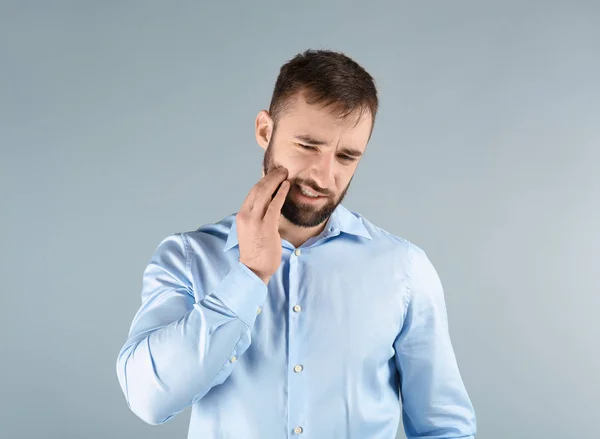 Young man suffering from toothache on light background — Stock Photo, Image