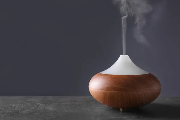 Aroma oil diffuser on table against color background