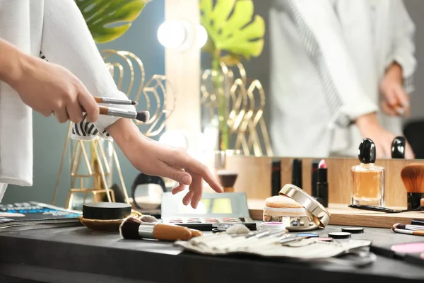 Профессиональный визажист у туалетного столика с декоративной косметикой в салоне красоты — стоковое фото