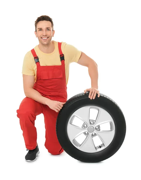 Jovem mecânico em uniforme com pneu de carro no fundo branco — Fotografia de Stock