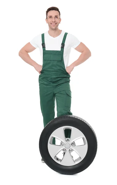 Joven mecánico en uniforme con neumático de coche sobre fondo blanco — Foto de Stock