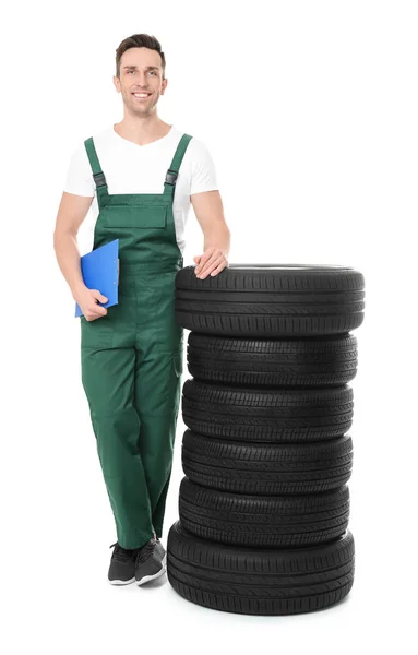 Молодий механік в уніформі з автомобільними шинами на білому тлі — стокове фото