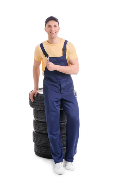 Mecánico masculino con neumáticos de coche sobre fondo blanco — Foto de Stock