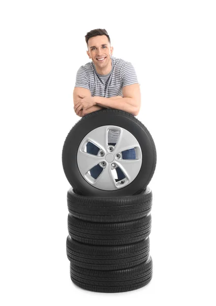 Hombre joven con neumáticos de coche sobre fondo blanco —  Fotos de Stock