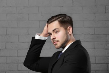 Tuğla duvar arka plan üzerinde güzel saçlı genç adam portresi