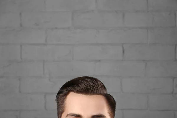 Человек с красивыми волосами на фоне кирпичной стены, крупным планом — стоковое фото