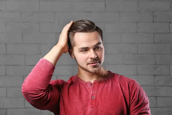 Retrato de hombre joven con hermoso cabello sobre fondo de pared de ladrillo — Foto de Stock