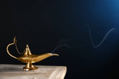 Aladdin magic lamp on table against dark background clipart