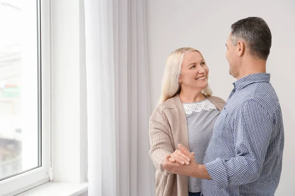 Feliz pareja de ancianos cerca de la ventana en casa — Foto de Stock